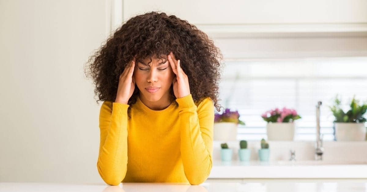 woman in yellow with a headache