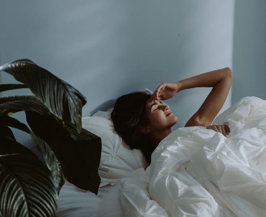 woman in bed touching her head