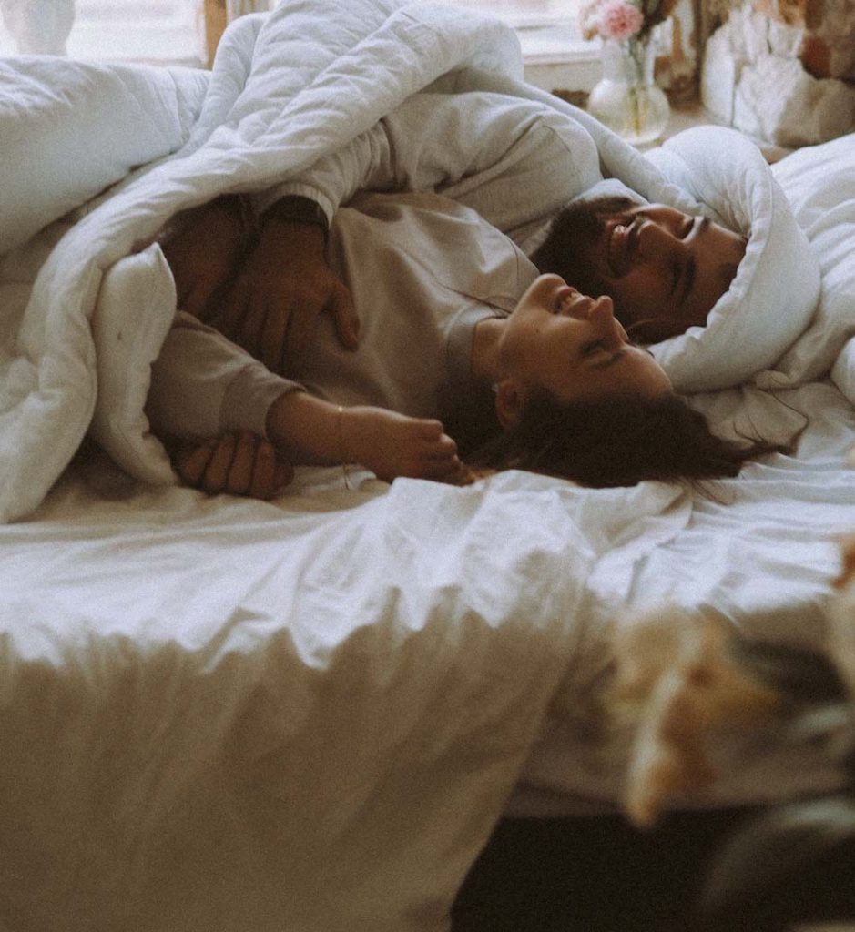woman and mad cuddling in bed