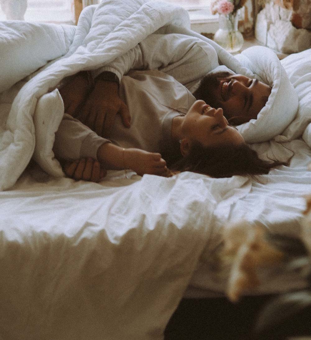 woman and mad cuddling in bed
